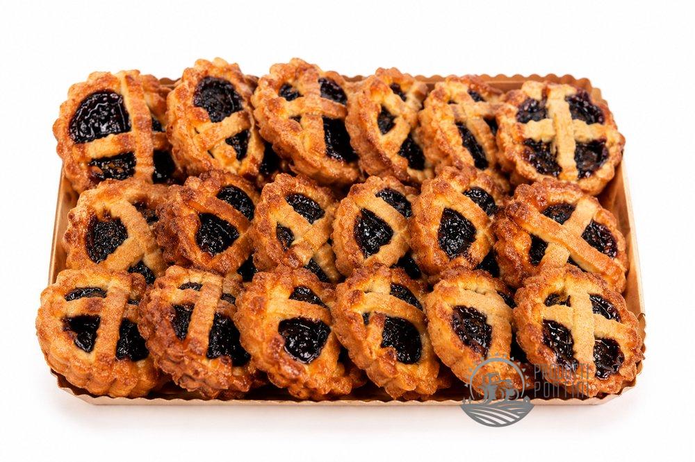 crostatine_visciole_sezze_web_200kb Tray of jam-filled thumbprint cookies with lattice crusts in a wooden box. Disks have golden-brown edges and dark berry centers.